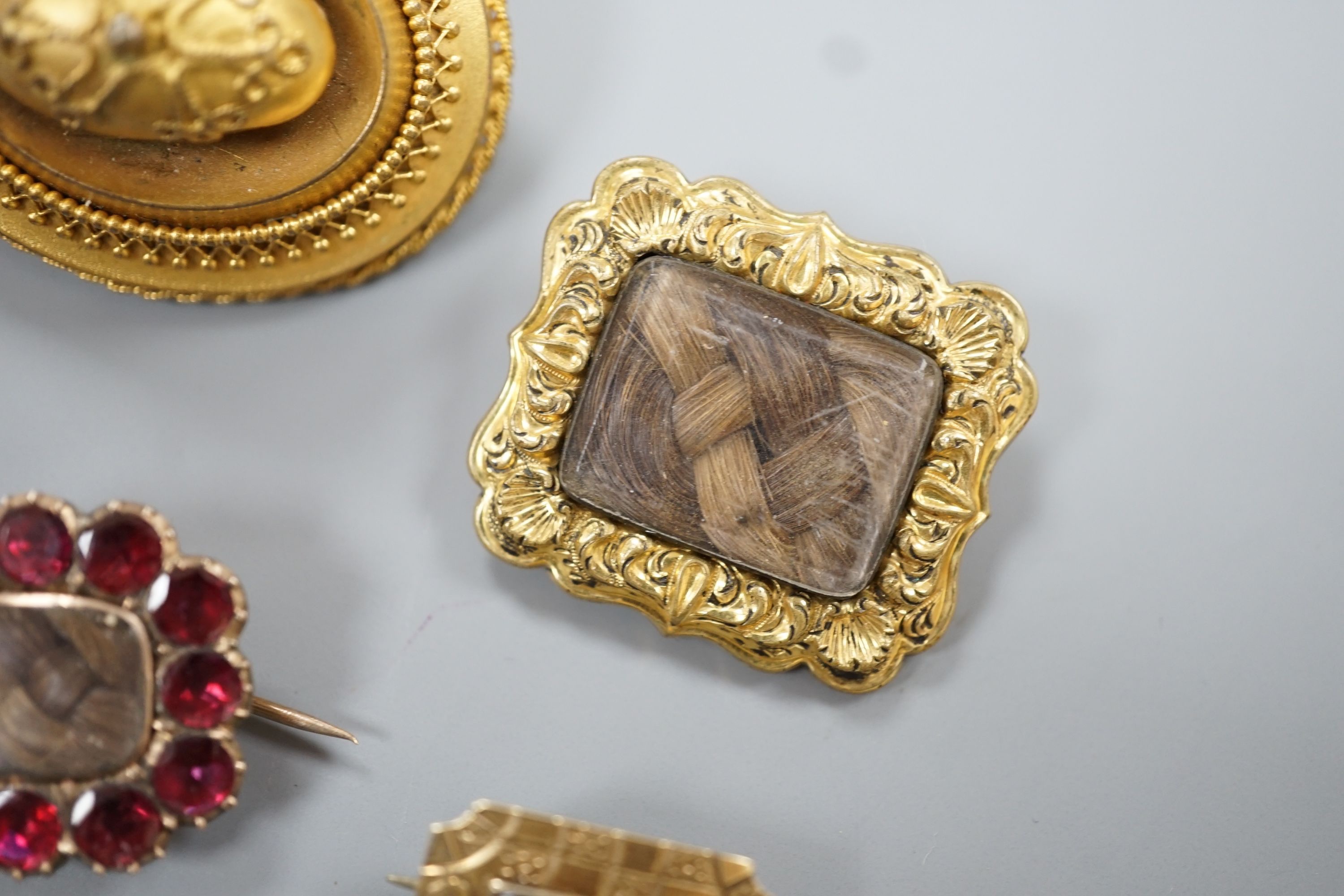 Two 19th century gilt metal and plaited hair set mourning brooches, two other mourning brooches and an oval pinchbeck brooch, largest 34mm.